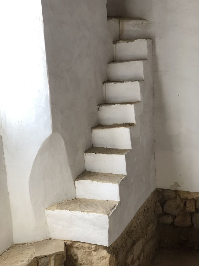 Narrow, steep stairs made of white stone, resembling a "death stairs" design in a rustic setting.