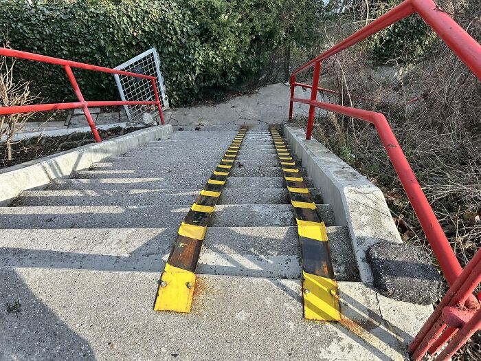 Concrete stairs with red railings, featuring yellow and black ramps, resembling "death stairs."