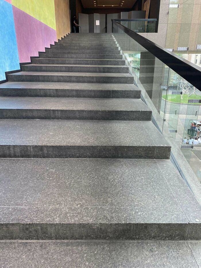 Steep gray "death stairs" with glass railings in a colorful building interior.