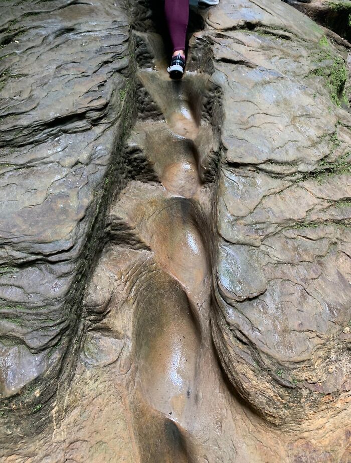 Person climbing worn rocky "death stairs," highlighting the natural erosion and challenging path.