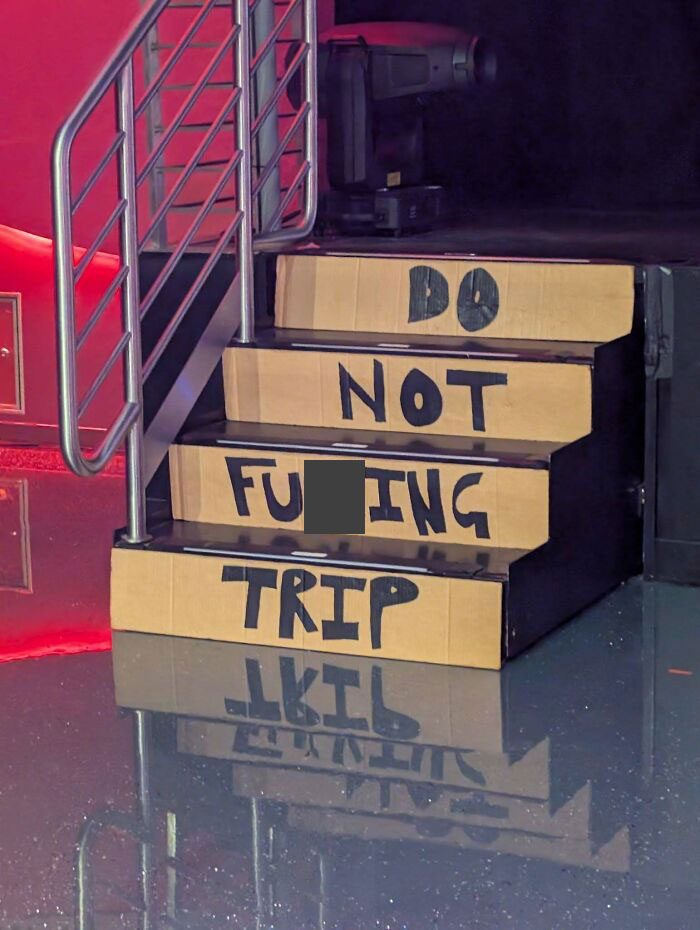 Stairs with warning message in bold letters, wrapped in cardboard, reflecting on a shiny floor; "death stairs" concept.