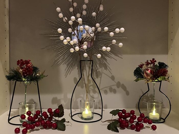 Three decorative metal vase holders with candles and faux red berries, styled to fake the fancy on a humble budget.