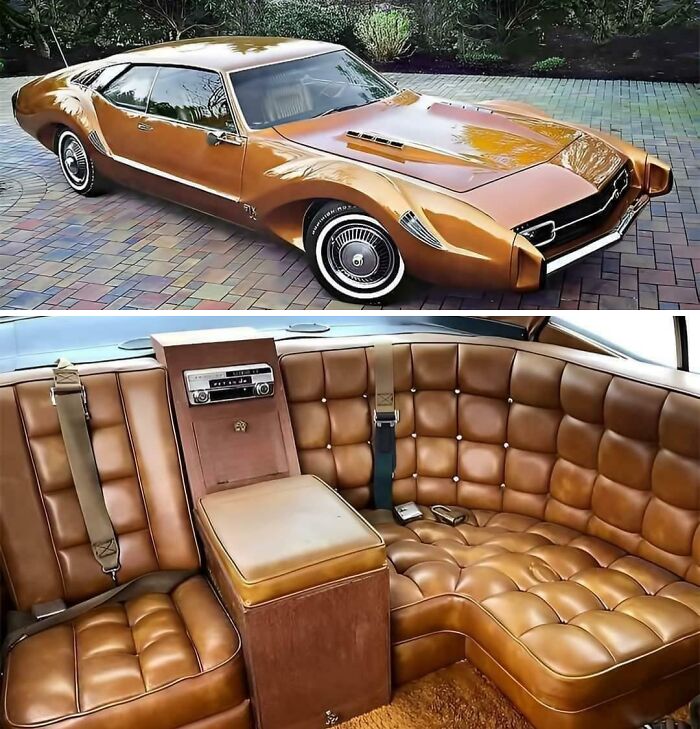 Vintage car with a sleek tan exterior parked on a brick driveway, featuring a luxurious leather interior.
