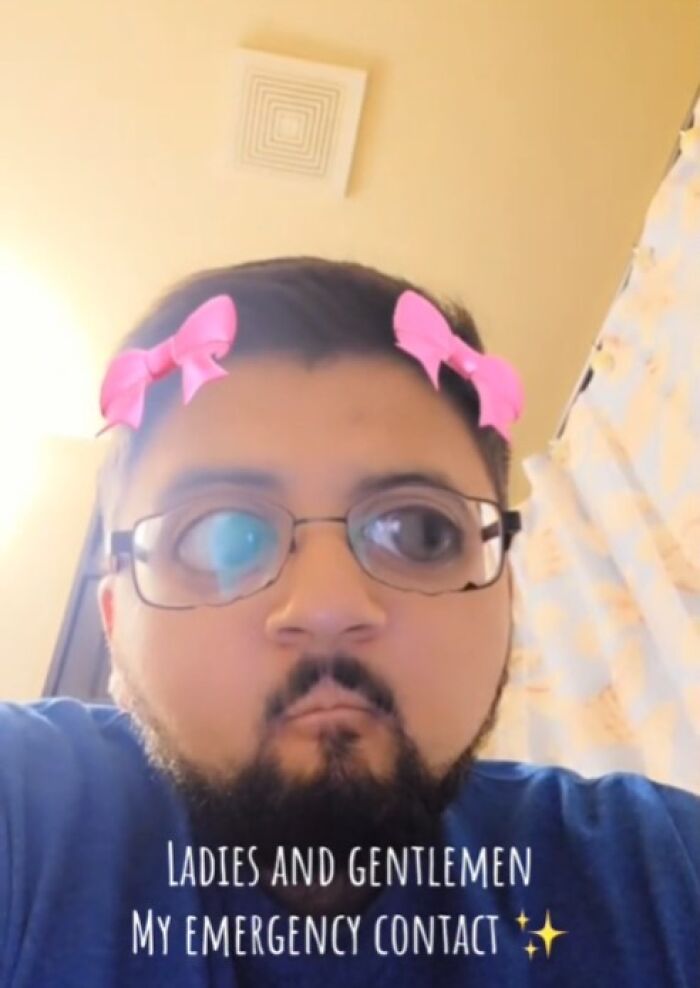 A man with cartoon glasses and pink bows filter, with text overlay about an emergency contact.