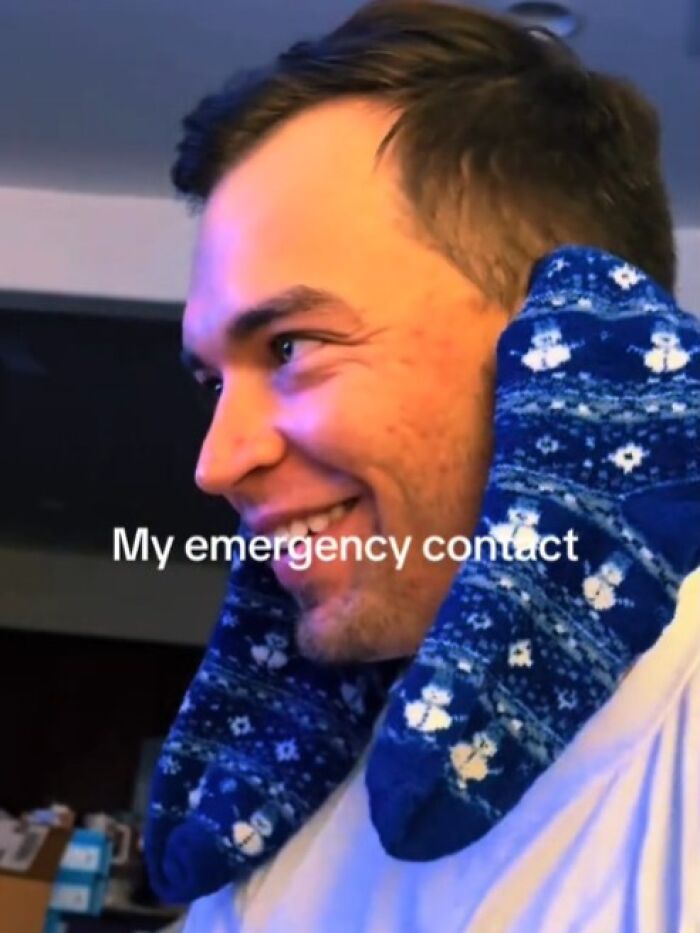 Man using blue socks as a neck pillow, humorously depicting a crisis in handling emergencies.