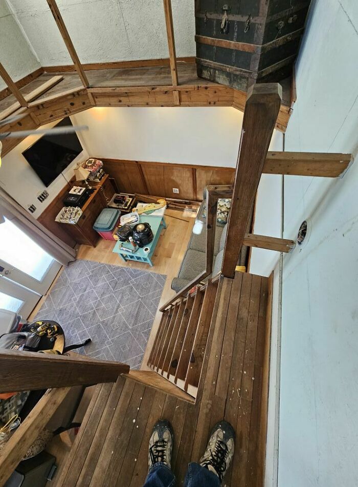 Narrow wooden stairway with a risky angle, cluttered room below, illustrating the concept of "death stairs."