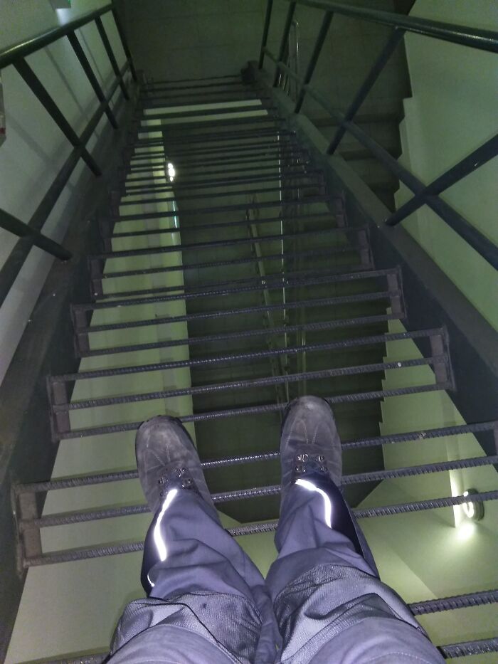 Feet on metal stairs with wide gaps, evoking the term "death stairs" for safety concerns.