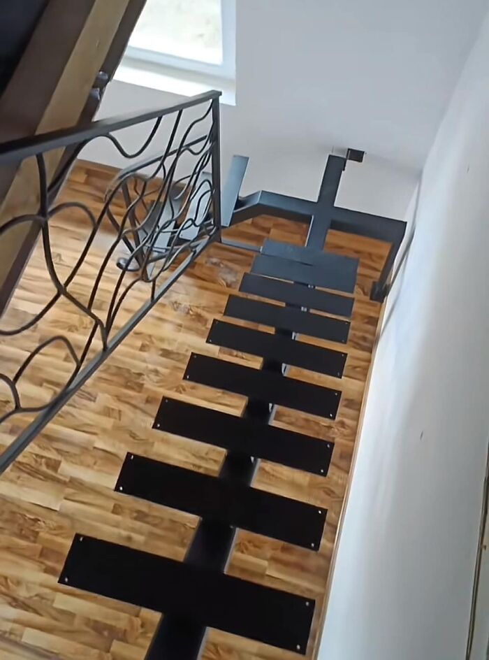 Unusual "Death Stairs" design with wide gaps, featuring a black metal frame and wooden flooring for a daring descent.