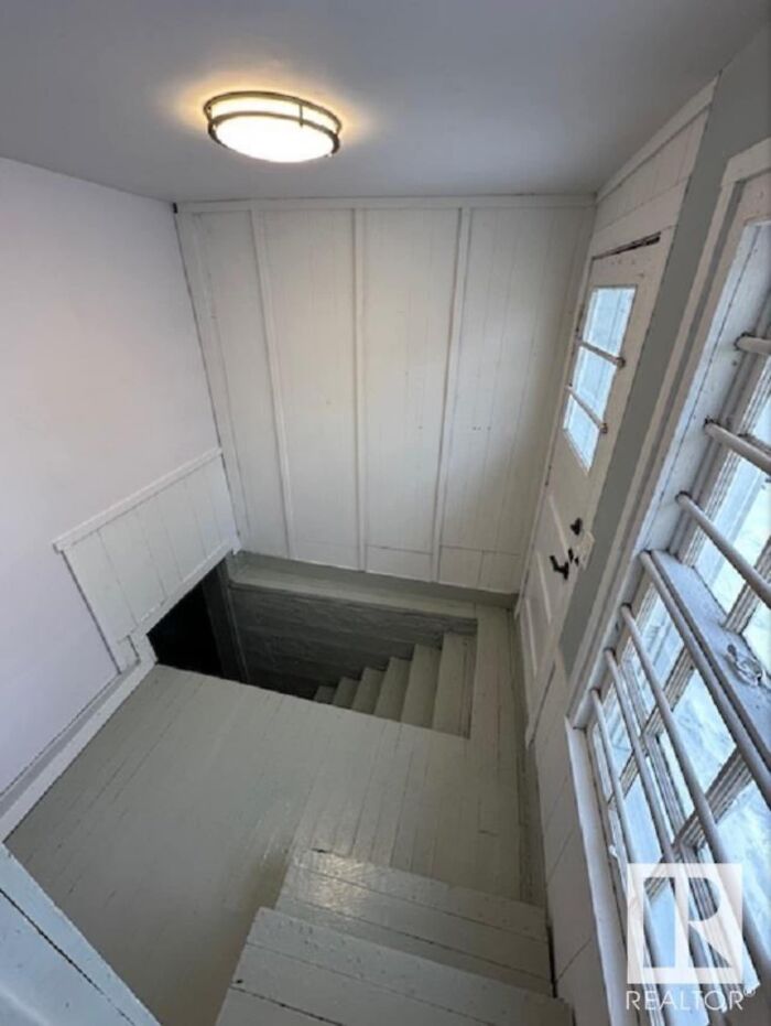 Steep indoor staircase with minimal railing, evoking a sense of danger associated with "death stairs".
