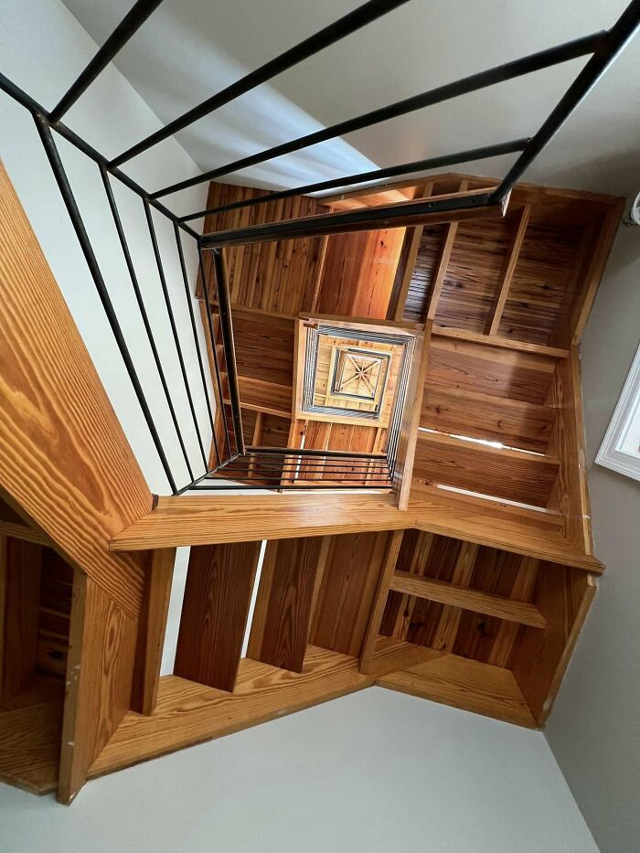 A dizzying spiral staircase with wooden steps, resembling "death stairs" from above, creates a vertigo effect.