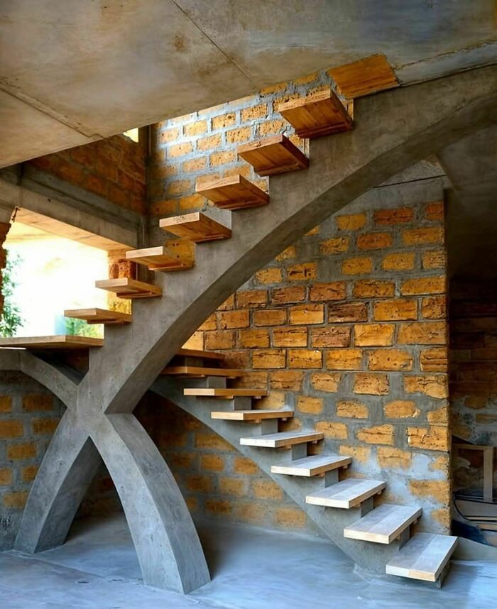 Modern staircase design with wooden steps and a concrete arch, resembling "death stairs."