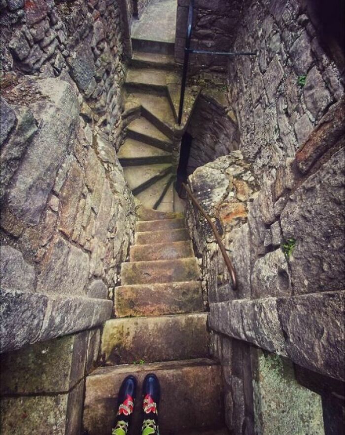 Narrow stone death stairs with a steep spiral design, surrounded by rocky walls, viewed from the top down.