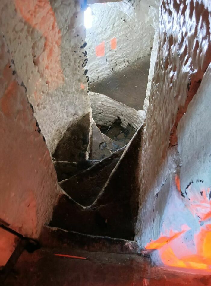 Narrow, winding stairs with uneven steps, often called "death stairs," inside a rustic stone building.