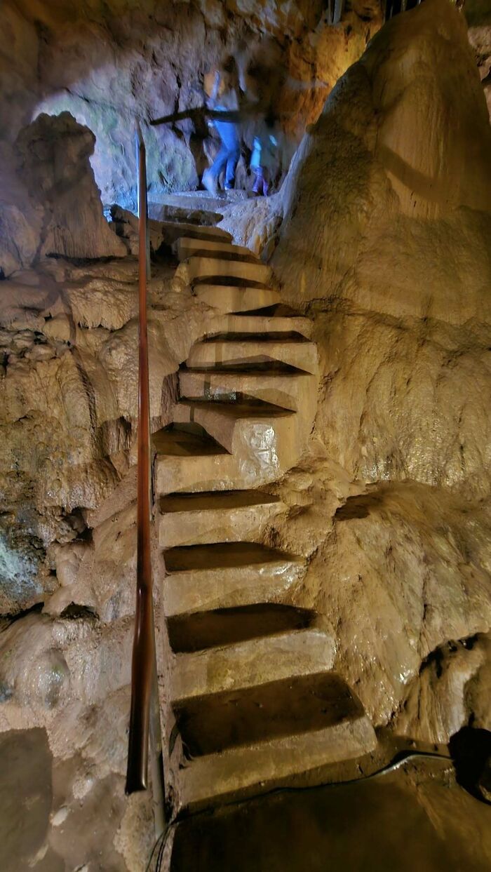 Steep, narrow "death stairs" carved into a rocky cave, casting an intimidating presence in dim lighting.