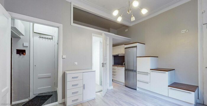 Modern kitchen with 'death stairs' leading to elevated storage, emphasizing compact and risky design choices.
