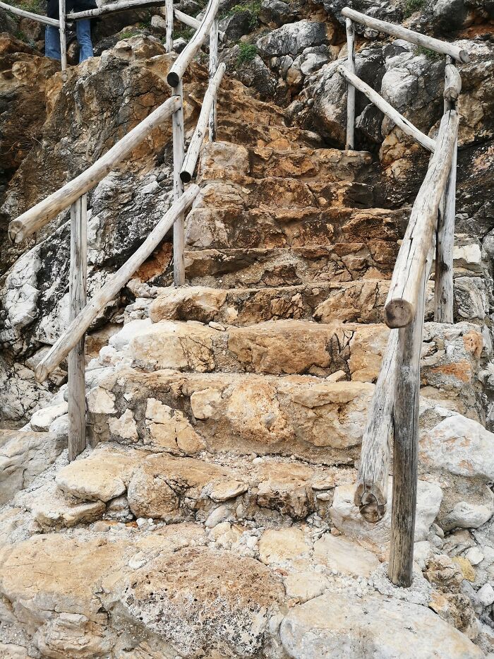 Rocky, uneven "death stairs" with wooden railing, leading upward through a rugged terrain.