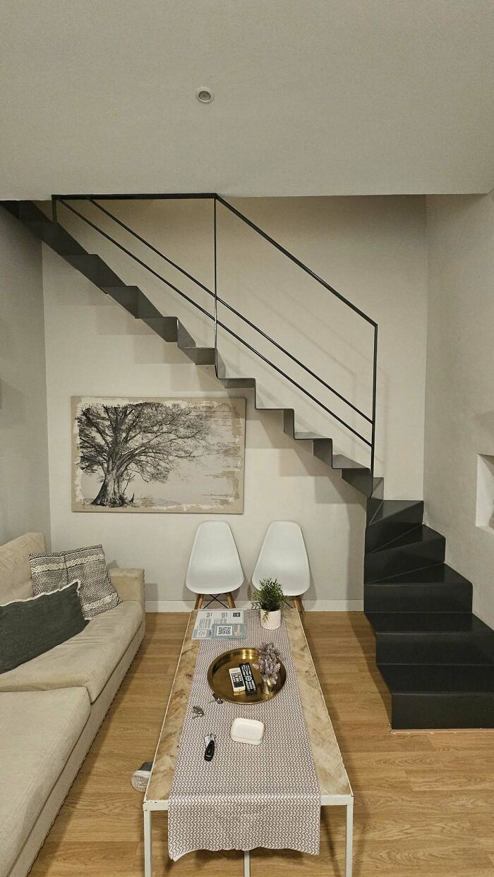 Modern black stairs with minimal railing in a stylish living room setting, showcasing "death stairs" concept.
