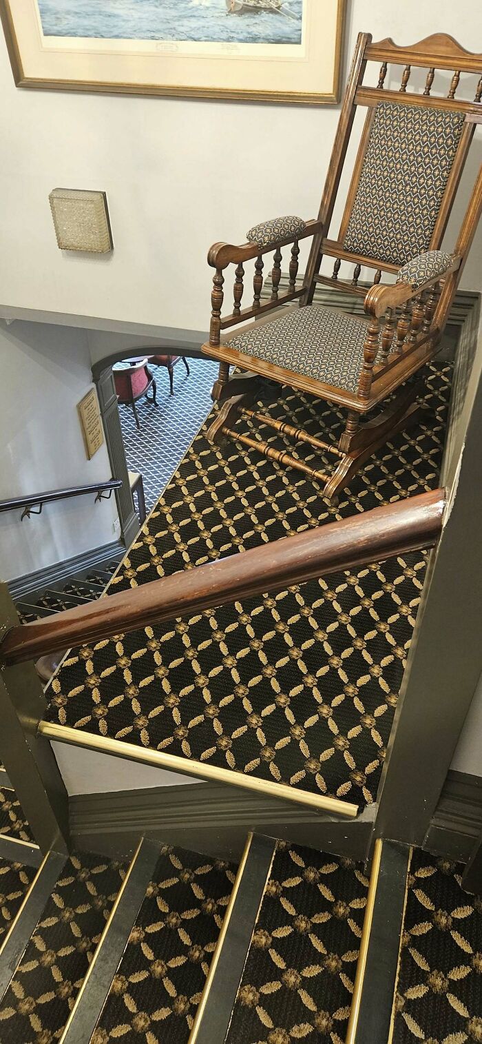 Chair precariously placed on patterned carpeted “death stairs” landing, creating a safety hazard.