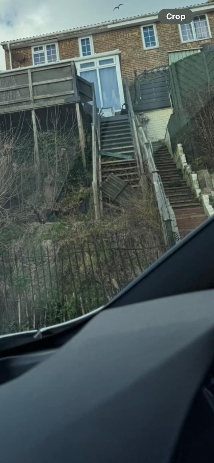 Steep outdoor stairs leading up to a house, with uneven steps and surrounding fences, known as "Death Stairs."