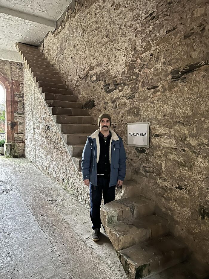 Man standing near steep stone stairs labeled "NO CLIMBING," illustrating the dangers of death stairs.