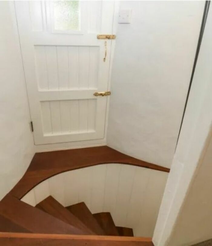 Narrow, steep wooden stairs with a white door at the top, often described as "death stairs."
