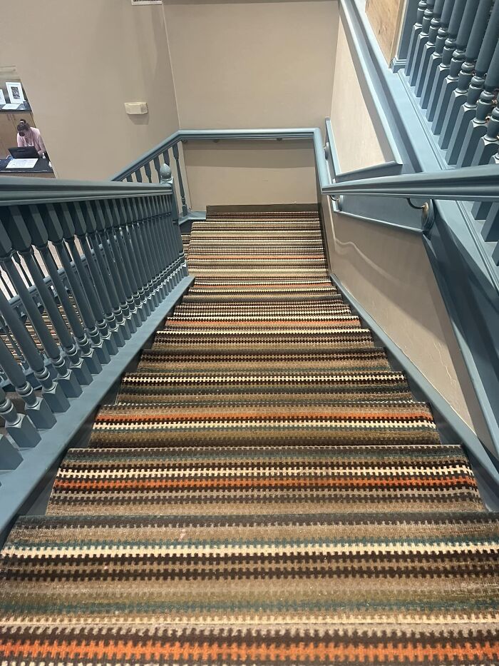 Steep, carpeted stairs with blue railings, illustrating "death stairs" concept.