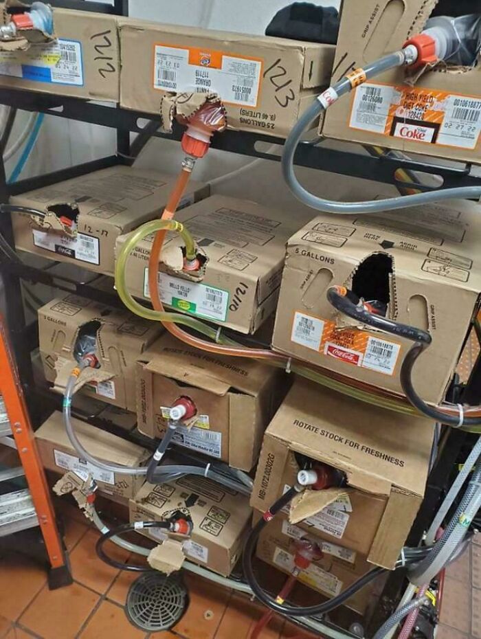 Soda syrup boxes with dispensing tubes provide a new perspective on beverage machinery in a stockroom setting.