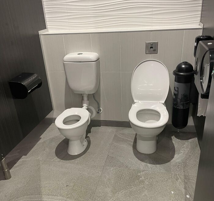 Two toilets side by side in a bathroom, showcasing an unusual design choice for Cities-Genius-Solutions.