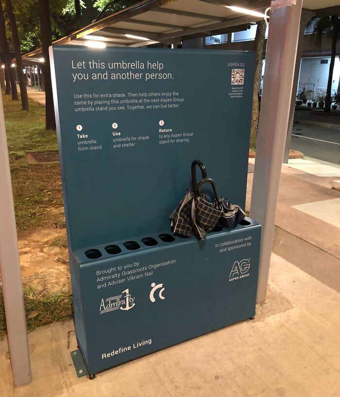 Umbrella sharing stand by Aspen Group for shade and shelter, showcasing Cities-Genius-Solutions in an urban setting.