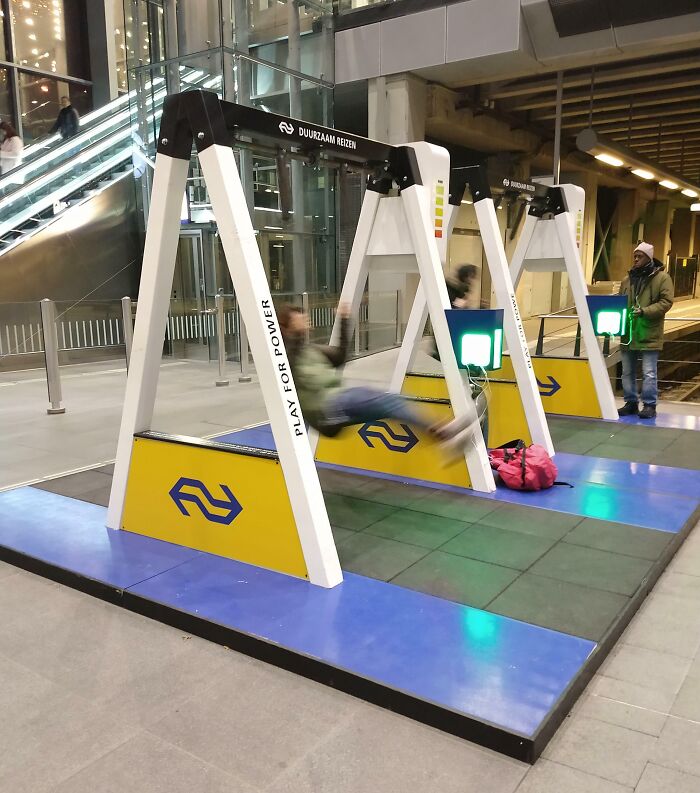 A person swinging on an energy-generating swing in a transit area, showcasing Cities-Genius-Solutions for sustainability.