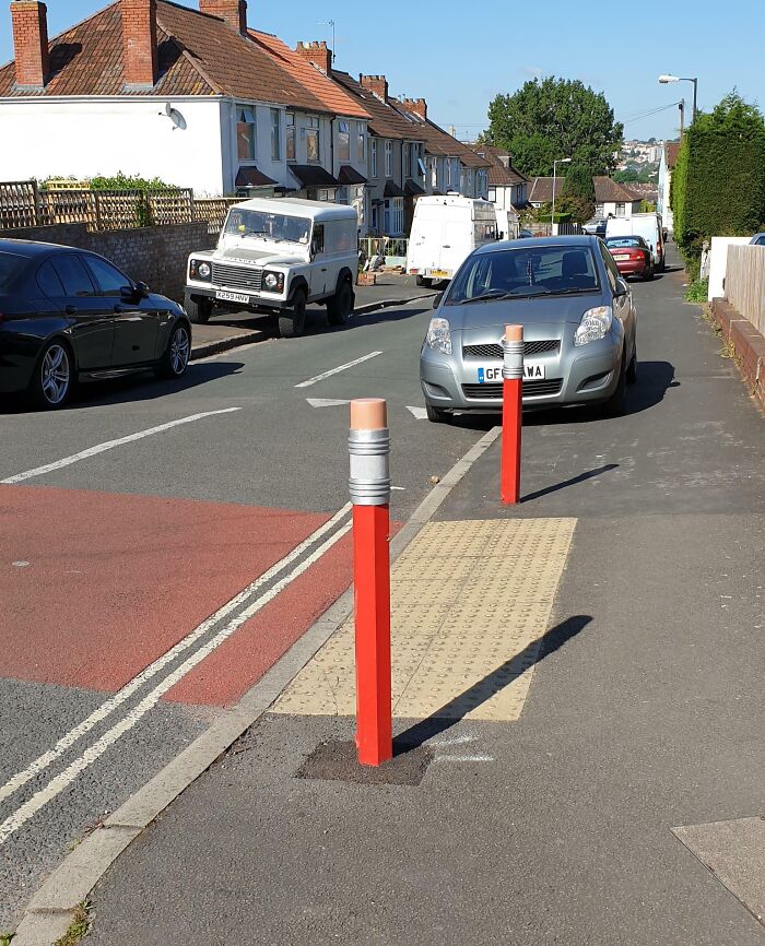 Red pencil-shaped bollards on a city street, part of Cities-Genius-Solutions for traffic management.