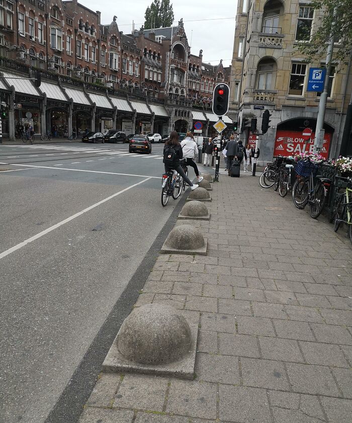 Cyclist navigating innovative urban barrier design in a busy city street, showcasing Cities-Genius-Solutions.
