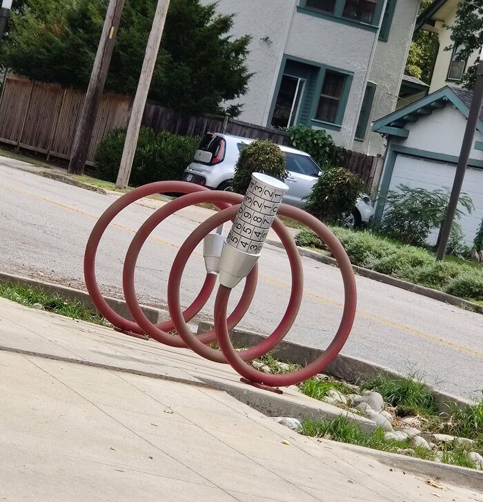 Red circular bike rack design resembling a bike lock, showcasing cities' genius solutions for urban infrastructure.