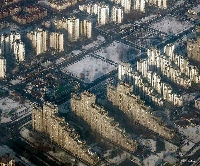 Aerial view of dense urban hell with identical high-rise buildings in a snowy landscape.