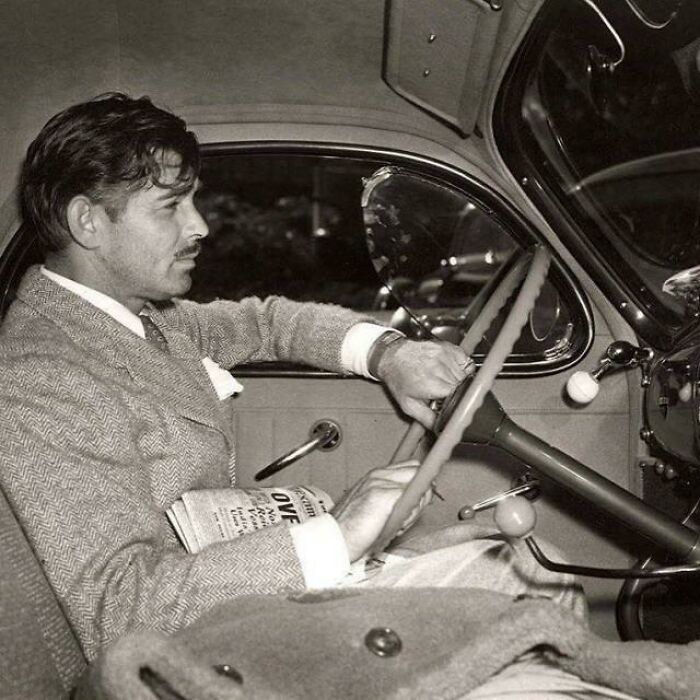 Person in vintage car holding a newspaper, showcasing something interesting seen from a past era.