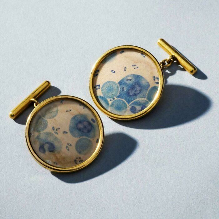 Gold cufflinks with blue artistic pattern, showing something interesting and unique.