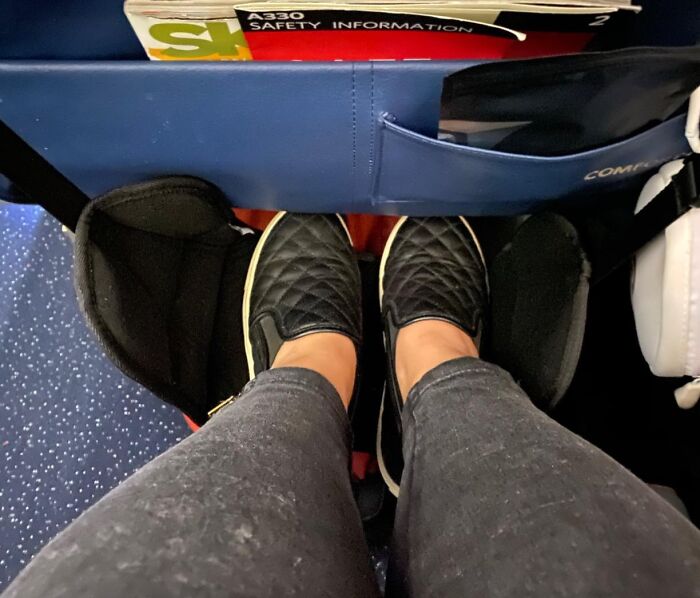 Feet in a hammock footrest on a plane, showcasing genius Amazon finds for travel comfort.