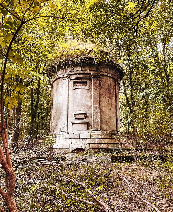 Overgrown stone structure surrounded by dense forest, showcasing nature reclaiming civilization.