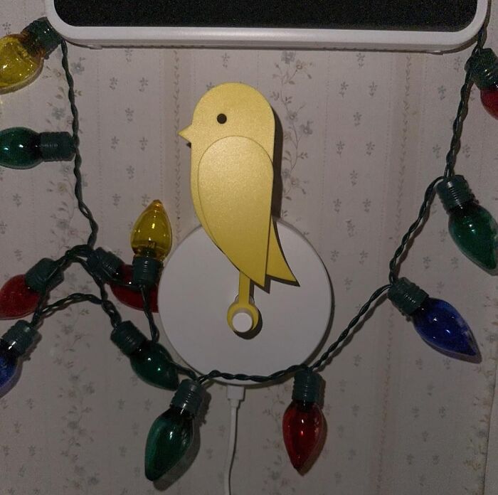 Yellow bird key holder on wall with colorful string lights.