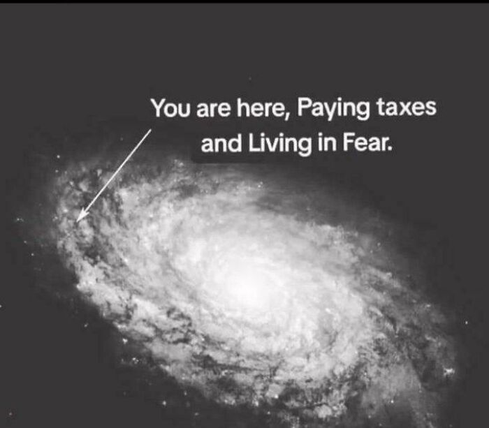 Galaxy image with text pointing and saying, "You are here, Paying taxes and Living in Fear," illustrating unsettling concept.