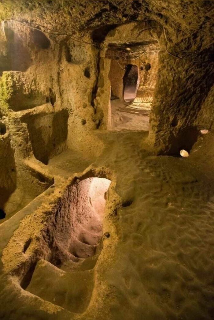 Underground ancient cave tunnel with carved stairs and passageways, showcasing strange earth formations and structures.