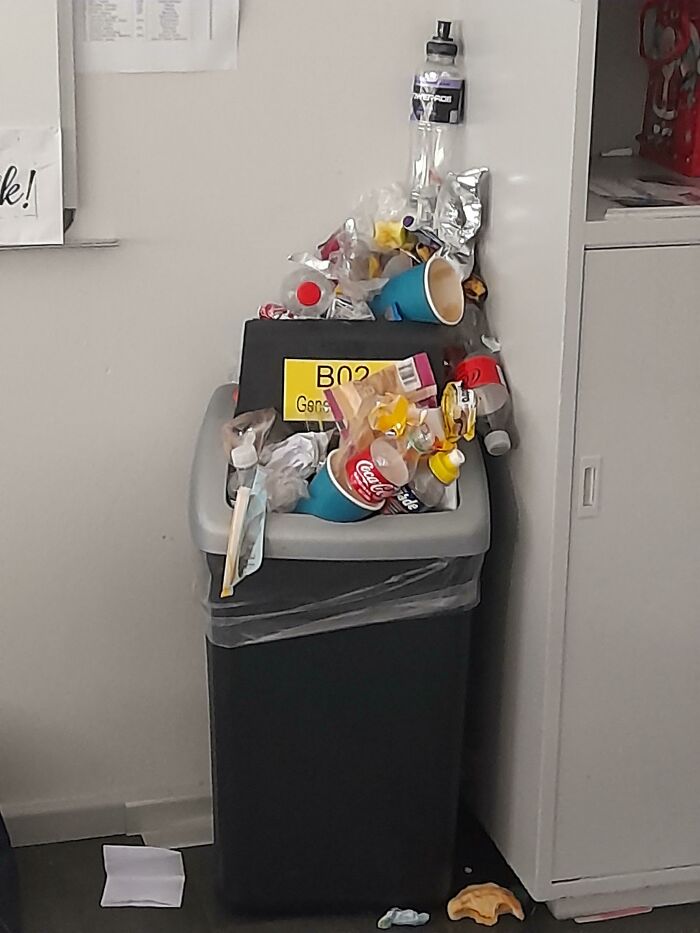 Papelera desbordante de basura en aula, símbolo de toxicidad y falta de profesionalidad en profesores.