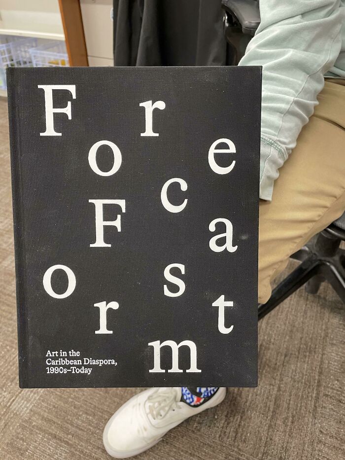 Poorly-Written-Designed-Books cover with jumbled lettering, held by a person in brown pants and white shoes.