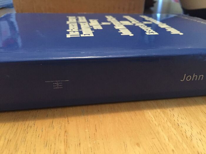 Poorly designed book cover lying flat on a wooden table, with blue color and unreadable white text.