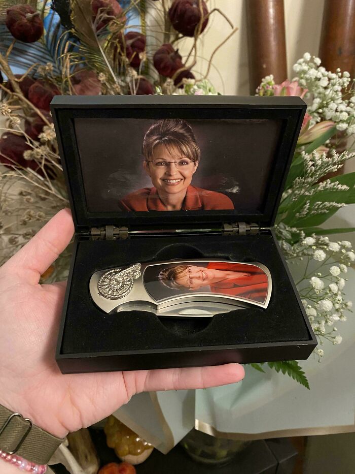 Hand holding a boxed knife with a custom photo handle, one of the best thrift store finds in a decorative floral background.