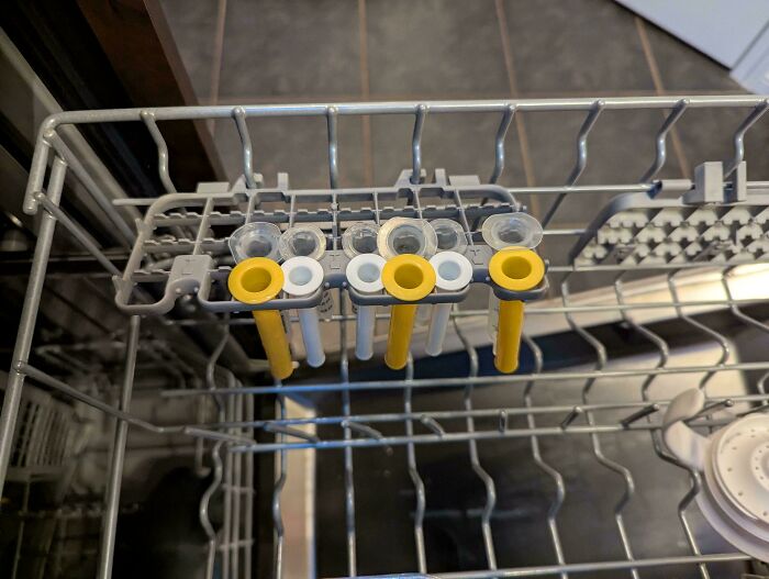 Dishwasher rack with baby bottle parts drying, illustrating dads doing their best parenting moments with feeding tasks.