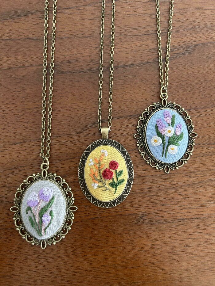 Three oval embroidery pendant necklaces with intricate floral designs on fabric, showcasing beautiful embroidery skills.