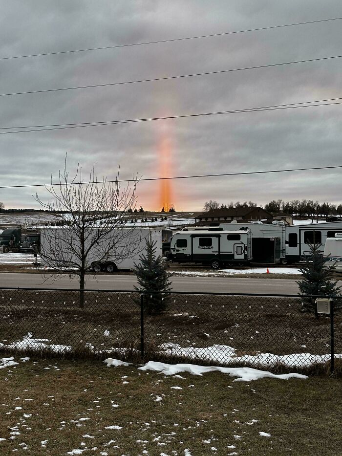 Pilar de luz al atardecer sobre un estacionamiento de caravanas, creando un efecto extrañamente aterrador.