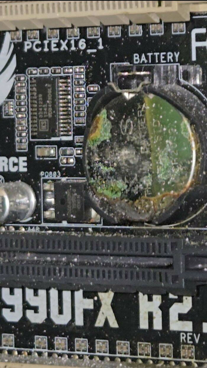 Corroded motherboard battery with visible damage and dust, representing tech support workers challenges and difficult hardware issues.