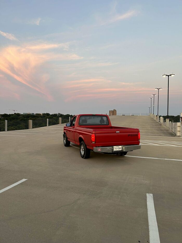 A red pickup truck parked on an empty parking garage rooftop at sunset, showcasing a Buy It For Life vehicle.